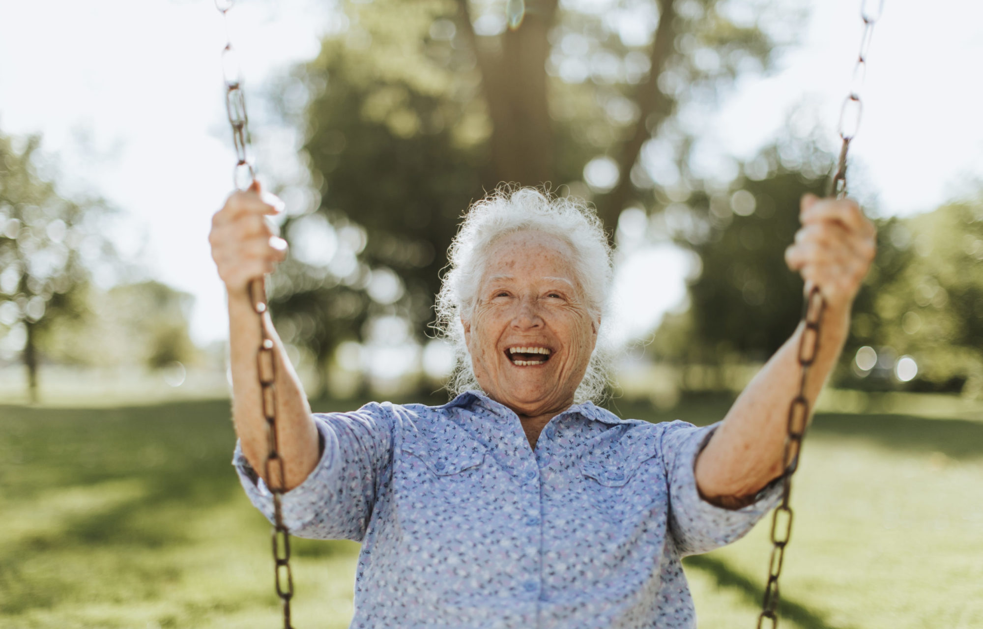 cheerful-senior-woman-on-swing-at-playground